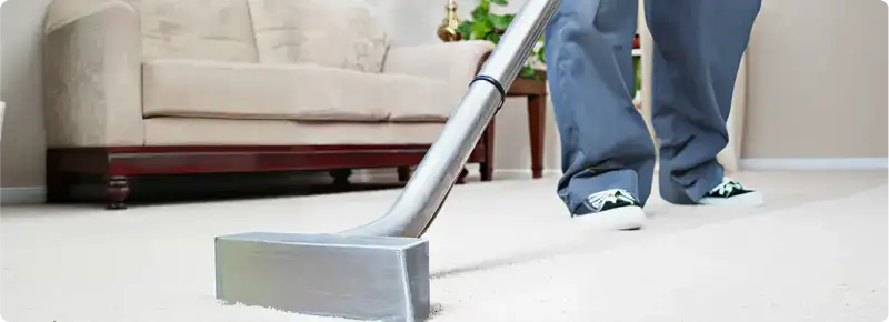 Carpet cleaning technician using a hot-water extraction wand on a light-colored carpet in a living room, Stamford, CT.
