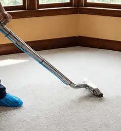 Steam carpet cleaning technician using a hot-water extraction wand on a residential carpet, wearing blue protective shoe covers Stamford, CT.