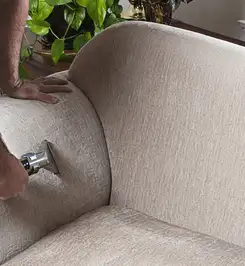 Professional upholstery cleaner deep-cleaning a fabric sofa with a handheld extraction tool and hose Stamford, CT.
